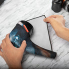 Person using a hair dryer on a piece of paper with a laptop and camera in the background.
