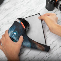 Person using a hair dryer on a piece of paper with a laptop and camera in the background.