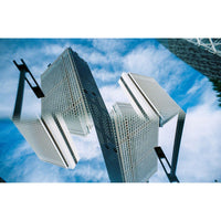 An architectural photograph of modern skyscrapers with a white grid pattern, captured from a dramatic low angle against a blue sky with white clouds.