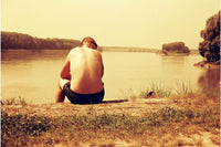 Man sitting by a lake with a scenic view