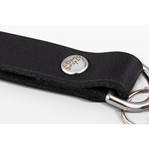 Close-up of a black textured leather keychain strap with a silver metal snap button engraved with 'long life' and silver key rings on a white background.