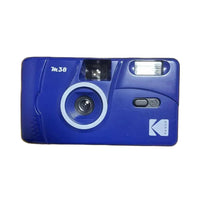 A vintage blue Kodak M.38 instant camera with a white circular ring around the lens, shown against a solid white background.