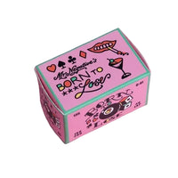 A pink rectangular product box with teal edges, decorated with retro-style black text reading 'Mr. Negative's BORN TO LOSE' and illustrated with playing cards, lips, a cocktail, and dice, set against a solid white background.