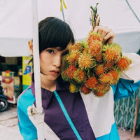 Person holding a bunch of colorful fruits with a blurred background