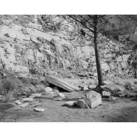 Black and white landscape photograph by Martin Zimelko depicting a rocky cliffside with scattered boulders, dry grass, and a solitary tree in the foreground.