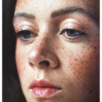 Portra 400 image of a close-up of a woman's face with freckles and blue eyes.