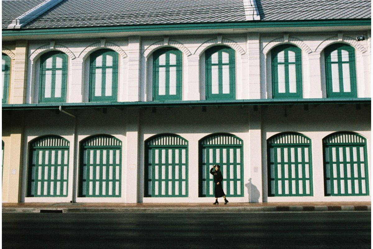 Person standing in front of a building with green windows