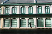Person standing in front of a building with green windows