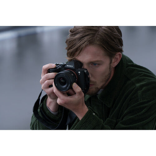 Man holding a Sony camera against a blurred background
