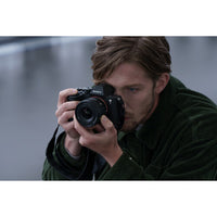 Man holding a Sony camera against a blurred background