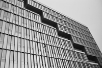 Black and white architectural photograph of a modernist building facade with stepped recesses and vertical window grilles.