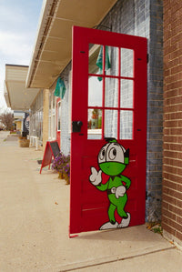 Red door with a cartoon character on it in front of a building