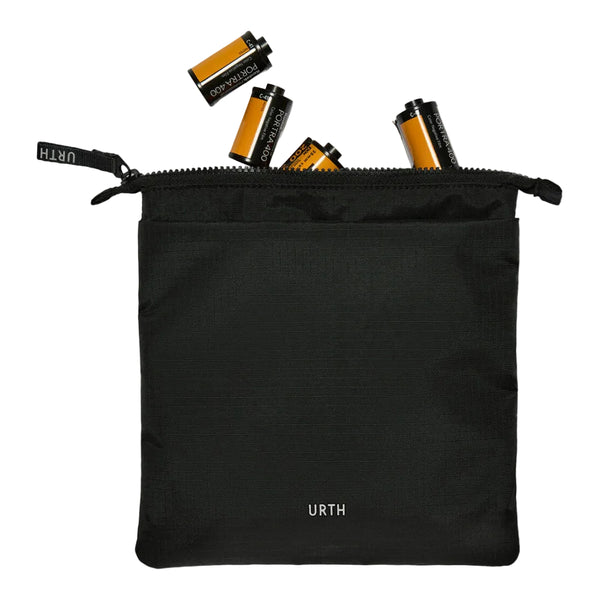 A black zippered pouch with the URTH logo printed in white near the bottom, shown on a white background with several film canisters spilling out from the top.