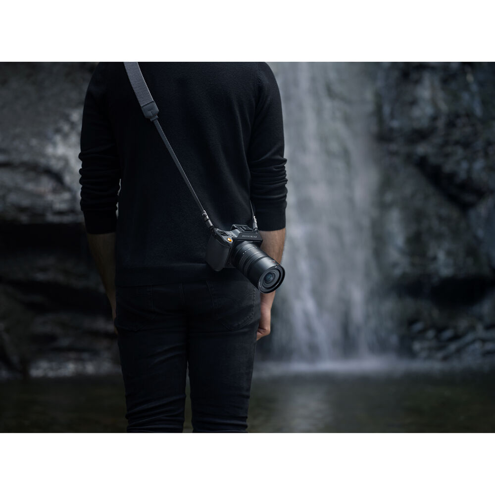 Person holding a camera with a waterfall in the background