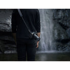 Person holding a camera with a waterfall in the background