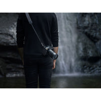 Person holding a camera with a waterfall in the background